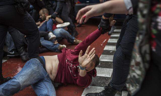 Polizisten zerren in Barcelona einen Demonstranten weg, der ein Abstimmungslokal schützen wollte.
