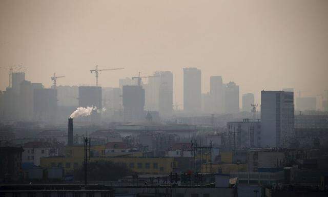 File photo of smoke rising from a chimney among houses as new high-rise residential buildings are seen under construction on a hazy day in the city centre of Tangshan