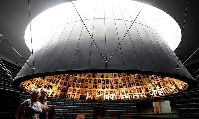 People look at pictures of Jews killed in the Holocaust during a visit to the Hall of Names in the Holocaust History Museum at the Yad Vashem World Holocaust Remembrance Center in Jerusalem, as Israel´s annual Holocaust Remembrance Day begins tonight