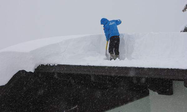 Ein Mann bei der Schneeräumung am Dach eines Hauses in Hochfilzen (Tirol) am Sonntag .