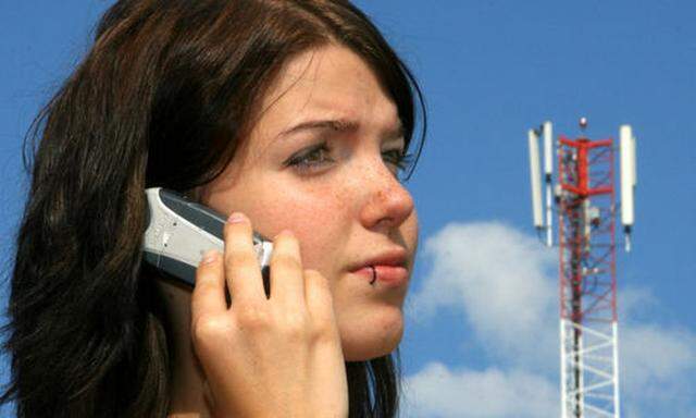 Frau mit Handy vor Handysendemast
