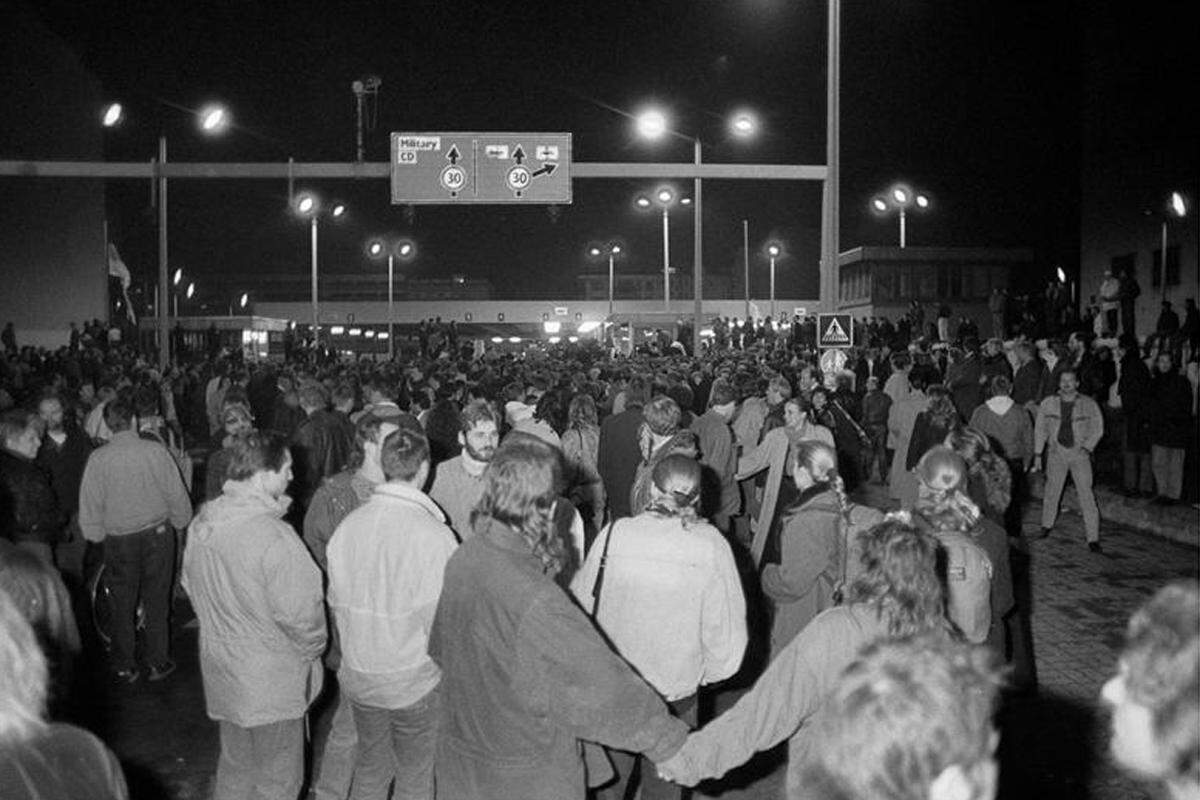 Am Checkpoint Charlie begrüßen in der Nacht des Mauerfalls Westberliner die über den Grenzübergang strömenden DDR-Bürger.