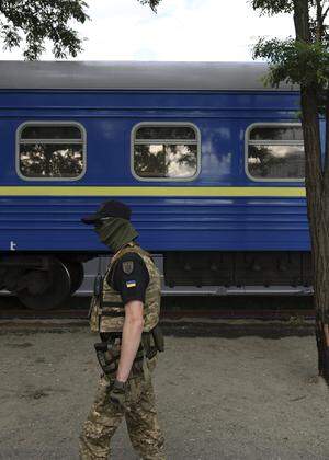 Ejn Soldat vor einem der blauen Waggons der ukrainischen Eisenbahn: Der Staatskonzern gilt  wegen seiner logistischen Schlüsselrolle als „zweite Armee“. 