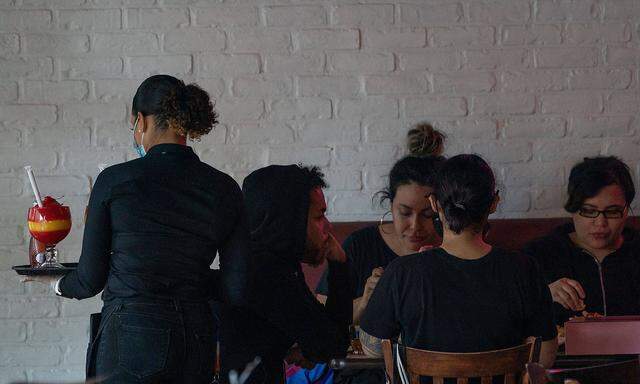 September 30, 2020, New York, New York, USA: A waitress serves a drink to customers inside at the Dallas BBQ in Chelsea