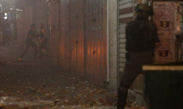 An Israeli border police aims his weapon at Palestinian stone throwers during clashes in the West Bank city of Ramallah