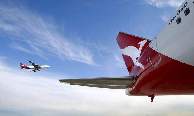 File photo of a Qantas Boeing 747 flying past a 767 airplane with a newly unveiled Qantas logo on its tail in Sydney