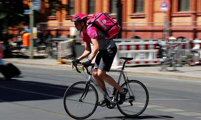 A Foodora delivery cyclist poses on a street in Berlin