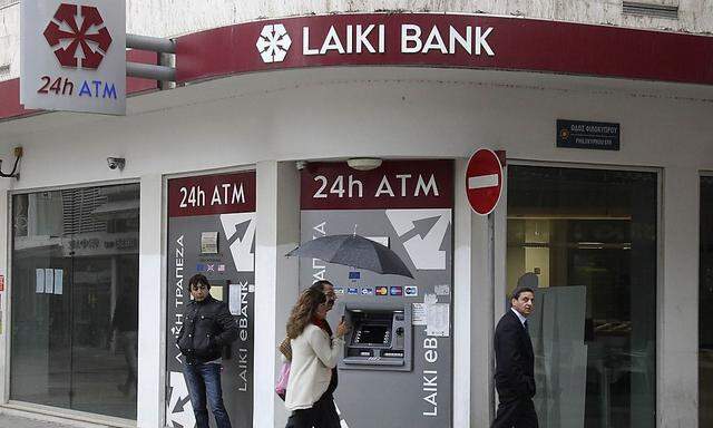 Cypriots walk pass a Cypriot bank on the island's capital Nicosia