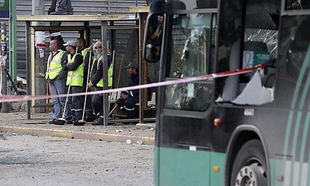Municipal workers stand in a bus stop near the scene of an explosion in Jerusalem