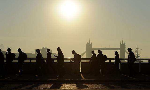 Workers cross London Bridge, with Tower Bridge seen behind, during the morning rush hour in London