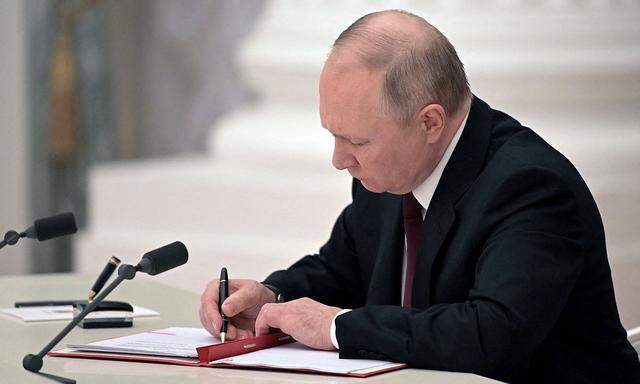 Russian President Vladimir Putin signs a decree recognising two Russian-backed breakaway regions in eastern Ukraine as independent entities during a ceremony in Moscow