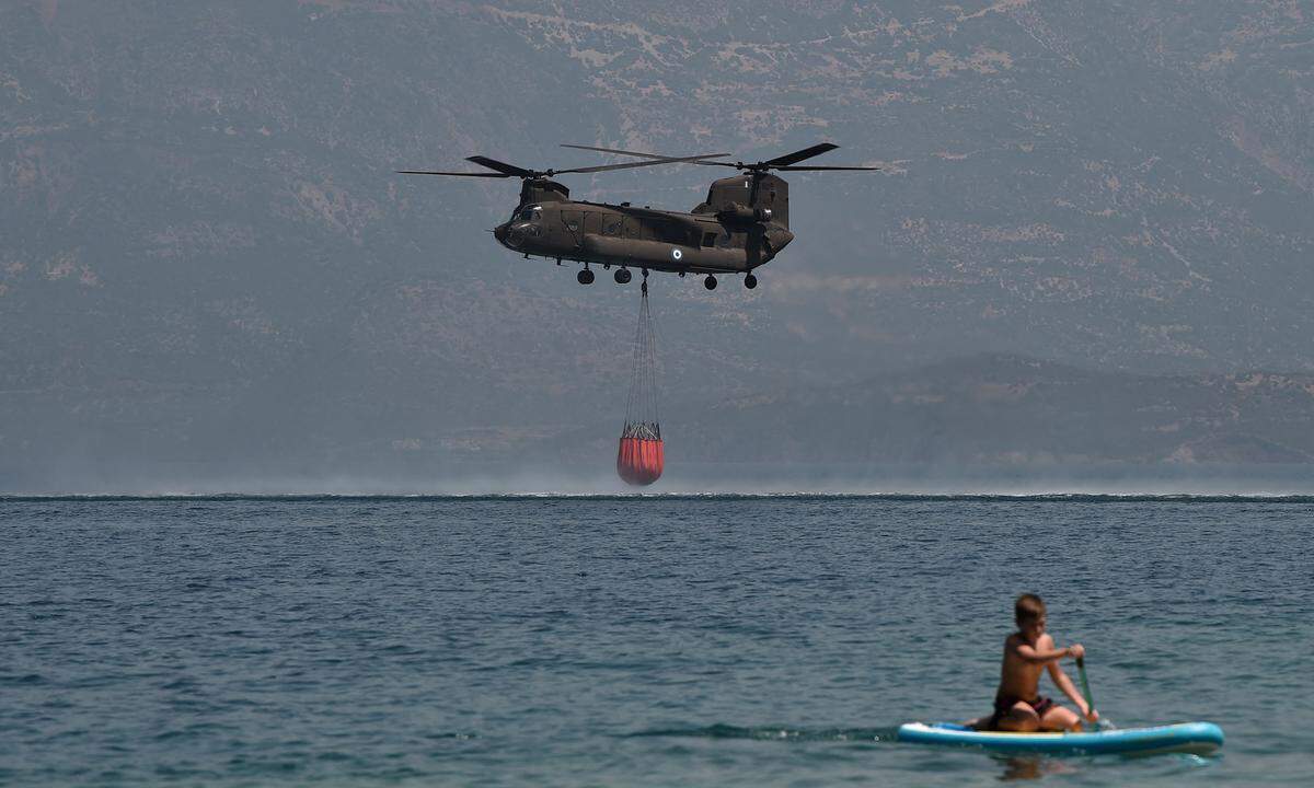 In Griechenland kämpften am Sonntag 300 Feuerwehrleute weiter gegen mehrere Brände auf dem Peloponnes. Im Bild: Ein CH-47D Chinook Helikopter wird am Strand von Labiri nahe der griechischen Stadt Patras von Badegästen beim Auffüllen des Löschtanks beobachtet.