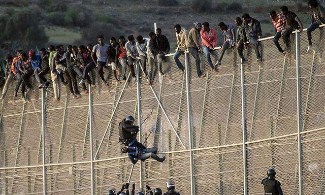 Polizisten versuchen Flüchtlinge von dem Zaun in Melilla zu holen. (Symbolfoto)