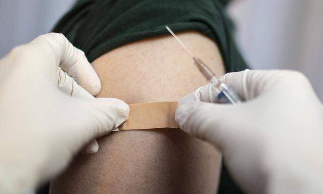Thema: Impfung. Arzt klebt ein Pflaster auf die Einstichstelle Bonn Deutschland *** Topic Vaccination Doctor sticks a p