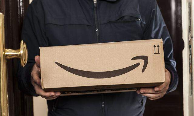 Postbote ueberbringt Amazon Paket Postbote ueberbringt Amazon Paket *** Postman brings Amazon package
