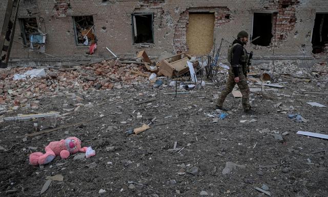 Ein ukrainischer Soldat vor einem zerstörten Gebäude in Tschassiw Jahr.