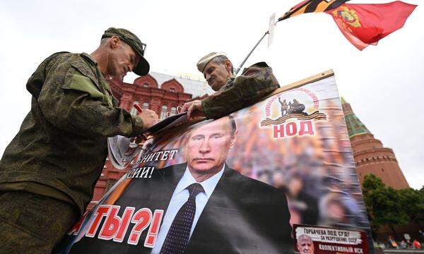 Soldaten auf dem Roten Platz mit einem Transparent des russischen Präsidenten, Wladimir Putin.