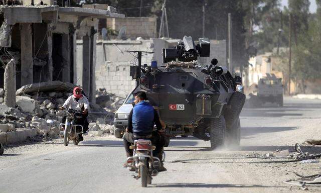 Men ride motorbikes past a Turkish armored carrier in the northern Syrian rebel-held town of al-Rai, in Aleppo Governorate