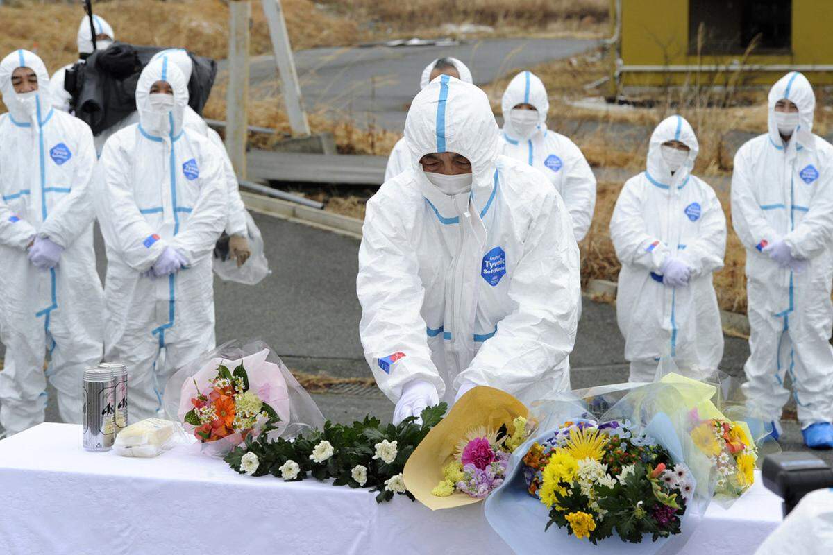 Auf der ganzen Welt haben am Sonntag die Menschen der Beben-, Tsunami- und Atomkatastrophe vor genau einem Jahr in Japan gedacht. Im Bild legen Angehörige von Opfern in der kontaminierten Zone beim Akw Fukushima Eins Blumen nieder.