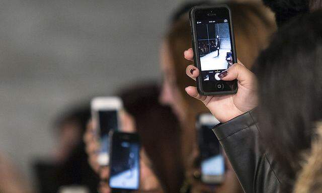 Attendees use cell phones to capture the presentation of the Parkchoonmoo 2014 Fall/Winter collection during New York Fashion Week