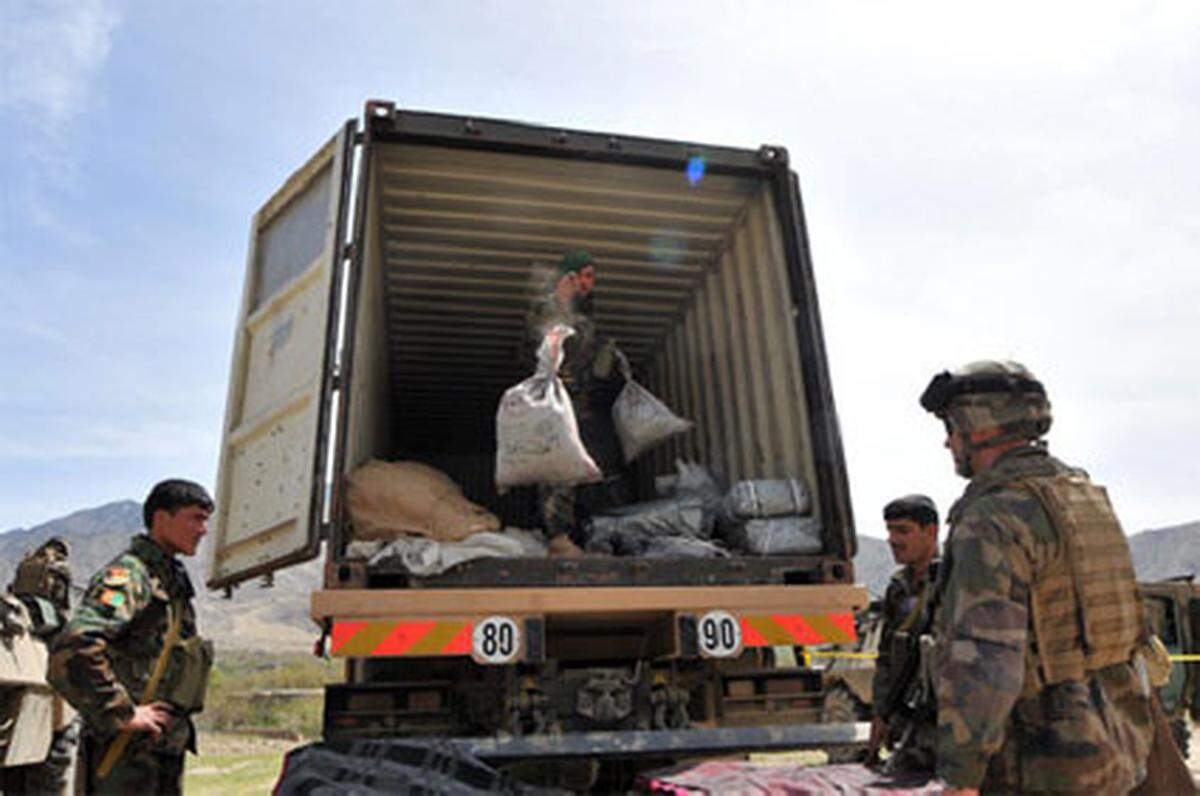 Hilfspaket wird zusammengestellt - hier fliegt ein Sack Holzkohle durch die Luft. Ort: Sultankhel, Provinz Kapisa.