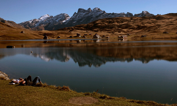 People relax during sunny autumn weather on the banks of Lake Melchsee near Melchsee-Frutt