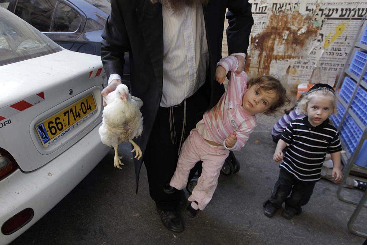 Jerusalem, Israel. Ein ultraorthodoxer Jude trägt in einer Hand ein Huhn, in der anderen seine Tochter. Juden auf der ganzen Welt haben das Versöhnungsfest Jom Kippur gefeiert.