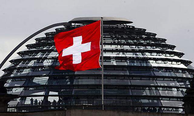 The Swiss national flag on top of Switzerlands embassy waves in the wind in front of the glass dome 
