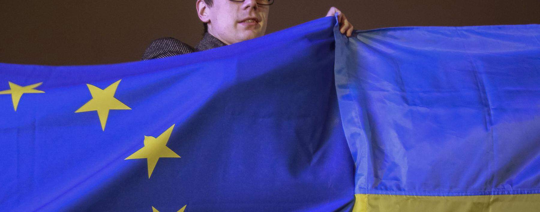 A protester holds Ukrainian and European Union flags during a rally to support euro integration in central Kiev