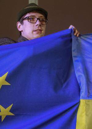 A protester holds Ukrainian and European Union flags during a rally to support euro integration in central Kiev