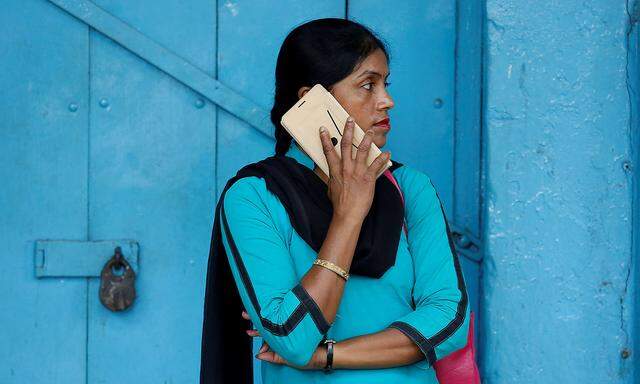 FILE PHOTO: A woman talks on her mobile phone on a pavement in Kolkata