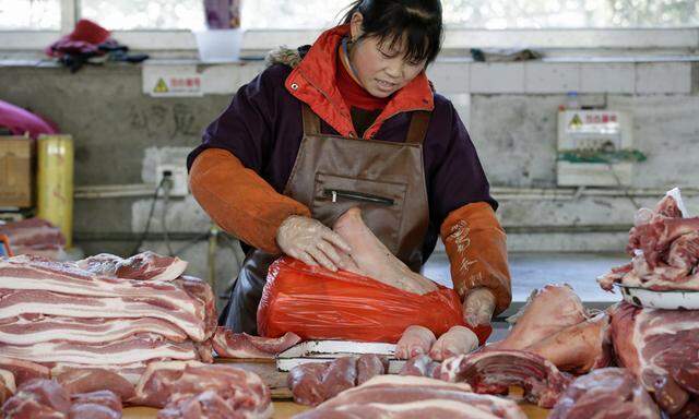 A pork butcher packs a pig´s head at a market in Beijing