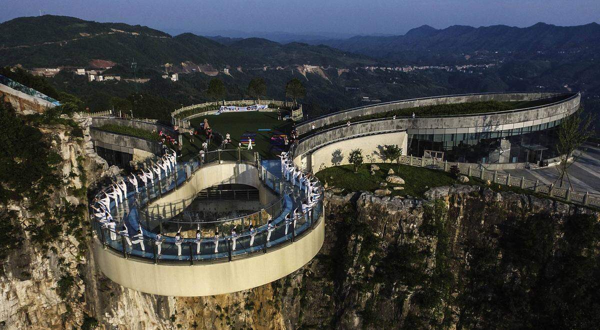 Copy/Paste? Im Yunyang Longgang Geological Park in Chongqing betrachten die Besucher die Aussicht über die Schlucht unter ihnen. Der Bau in 1123 Meter Höhe ist die längste frei tragende Glasbodenbrücke der Welt. 27 Meter weit ragt die Konstruktion von der Felskante ins Freie. Der zuvor erbaute und optisch sehr ähnliche Grand-Canyon-Skywalk kommt nur auf 22 Meter.