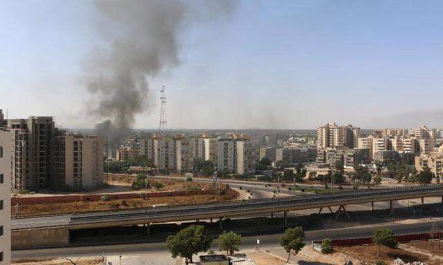 Smoke rises near buildings after heavy fighting between rival militias broke out near the airport in Tripoli