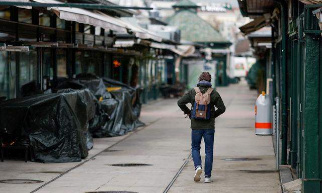 FILE PHOTO: A person passes closed restaurants and shops at a market after the local government extended the lockdown due to the coronavirus disease (COVID-19) outbreak in Vienna,