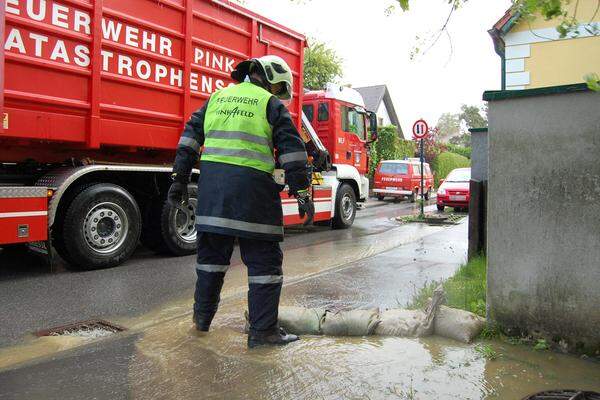 Freitag, 10:30 Uhr. Ein Feuerwehrmann im Einsatz gegen das Wasser auf einer Straße im Raum Pinkafeld.