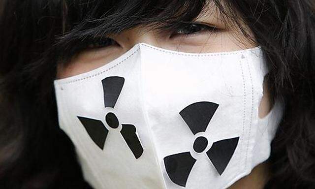 An anti-nuclear protester wearing a mask with the symbol for radioactivity participates in a march in