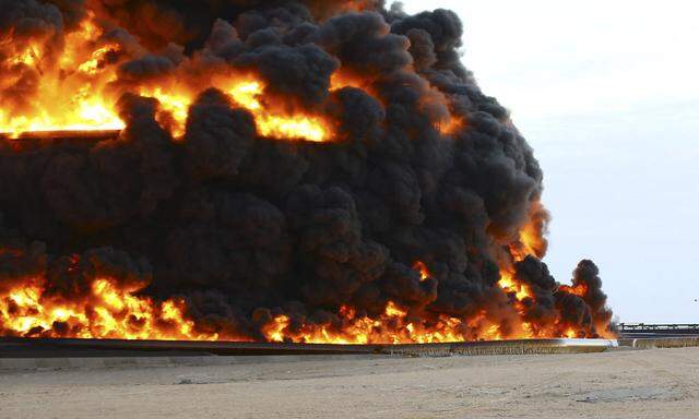 Firefighters try to put out the fire in an oil tank in Es Sider port