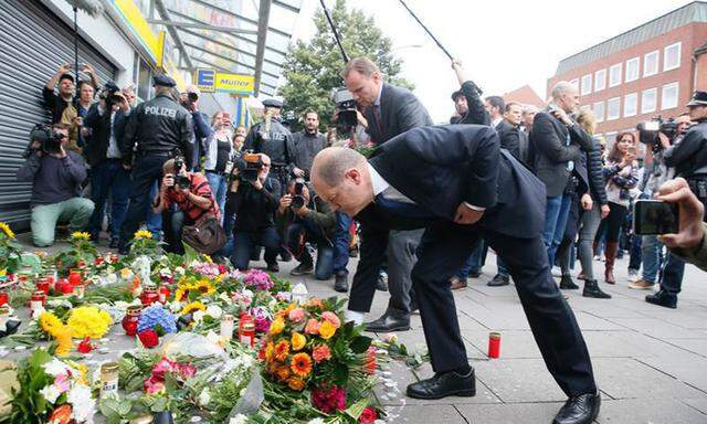 Hamburgs Bürgermeister, Olaf Scholz (SPD), legt Blumen an dem improvisierten Mahnmal nieder.