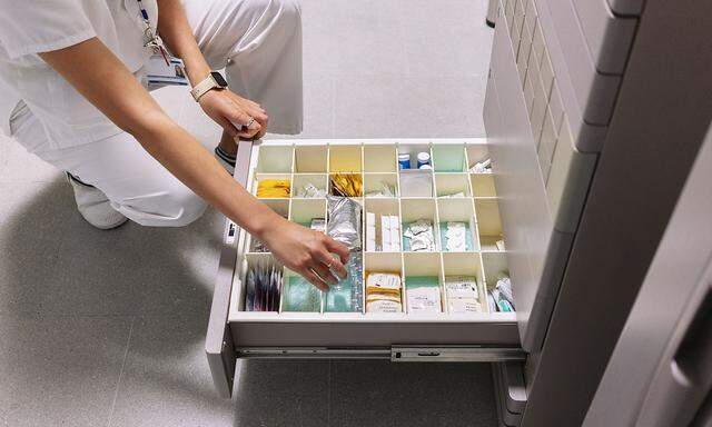 Female doctor searching medicines in drawer at pharmacy