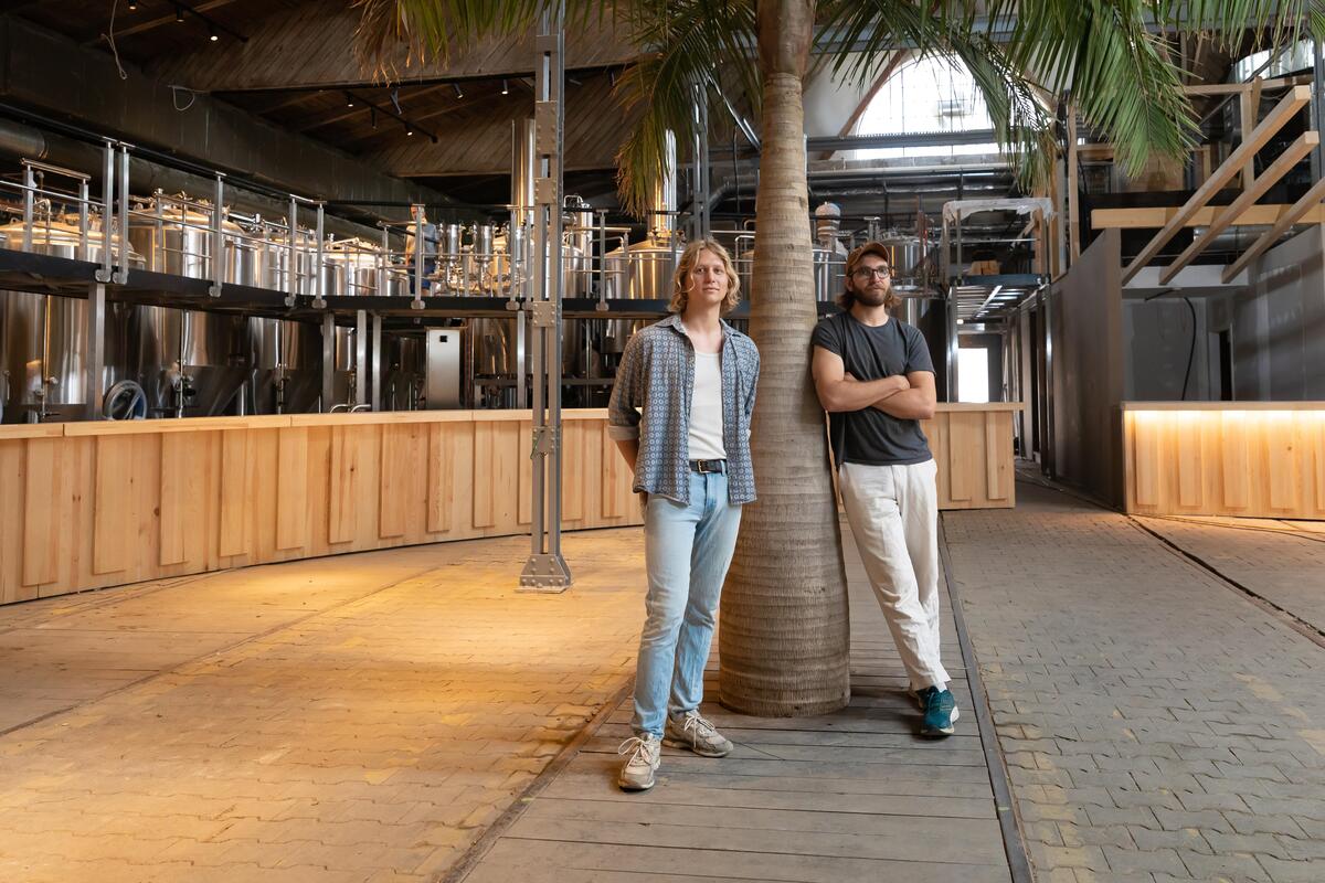 Im Gleisgarten: Betreiber Felix Bollen (li.) und Anton Borkmann unter einer Palme und vor der Bierbrauerei. Die Schienen der alten Remise haben sie bewusst erhalten.