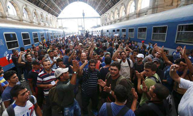 Migrants gesture as they stand in the main Eastern Railway station in Budapest