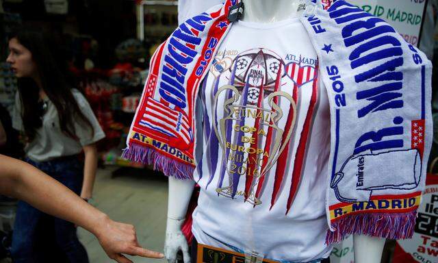 A woman points at a souvenir t-shirt of the UEFA Champions League Final between Atletico Madrid and Real Madrid at a souvenir store in downtown Madrid