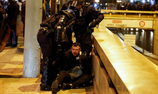 Polizisten nehmen einen Demonstranten fest.