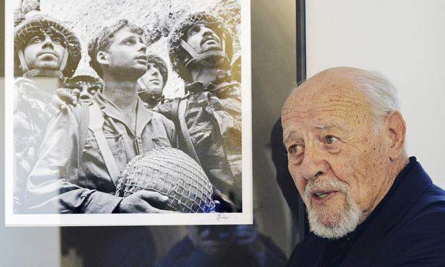 Israeli photographer David Rubinger pose by his famous photo of three Israeli paratroopers after the