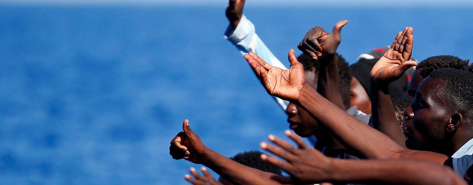 Gerettet im Mittelmeer. Flüchtlinge, die vor Libyens Küste in Seenot geraten sind, winken Helfern der NGO SOS Méditerranée.  