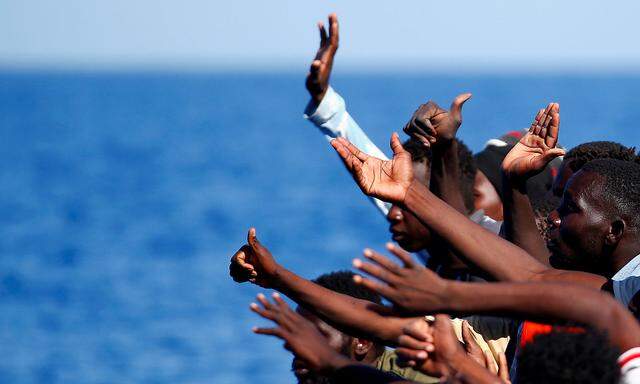 Gerettet im Mittelmeer. Flüchtlinge, die vor Libyens Küste in Seenot geraten sind, winken Helfern der NGO SOS Méditerranée.  