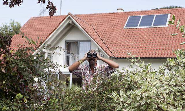 Man looking through binoculars over hedge model released Symbolfoto property released PUBLICATIONxIN