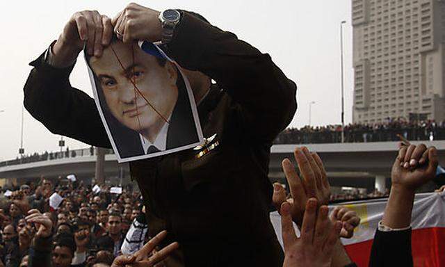 An army officer who joined anti-government protester tears up a picture of Egyptian President Hosni M