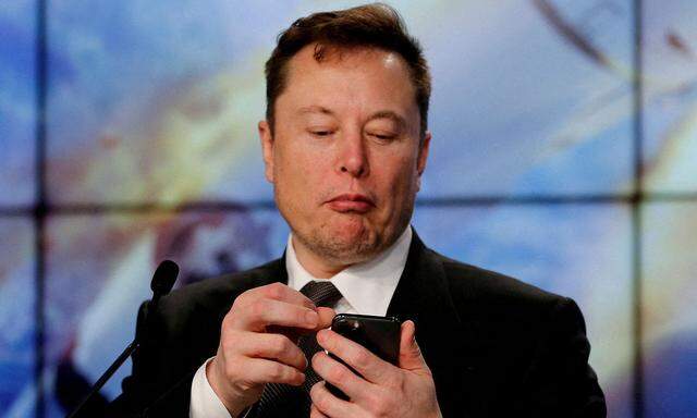 FILE PHOTO: Elon Musk looks at his mobile phone